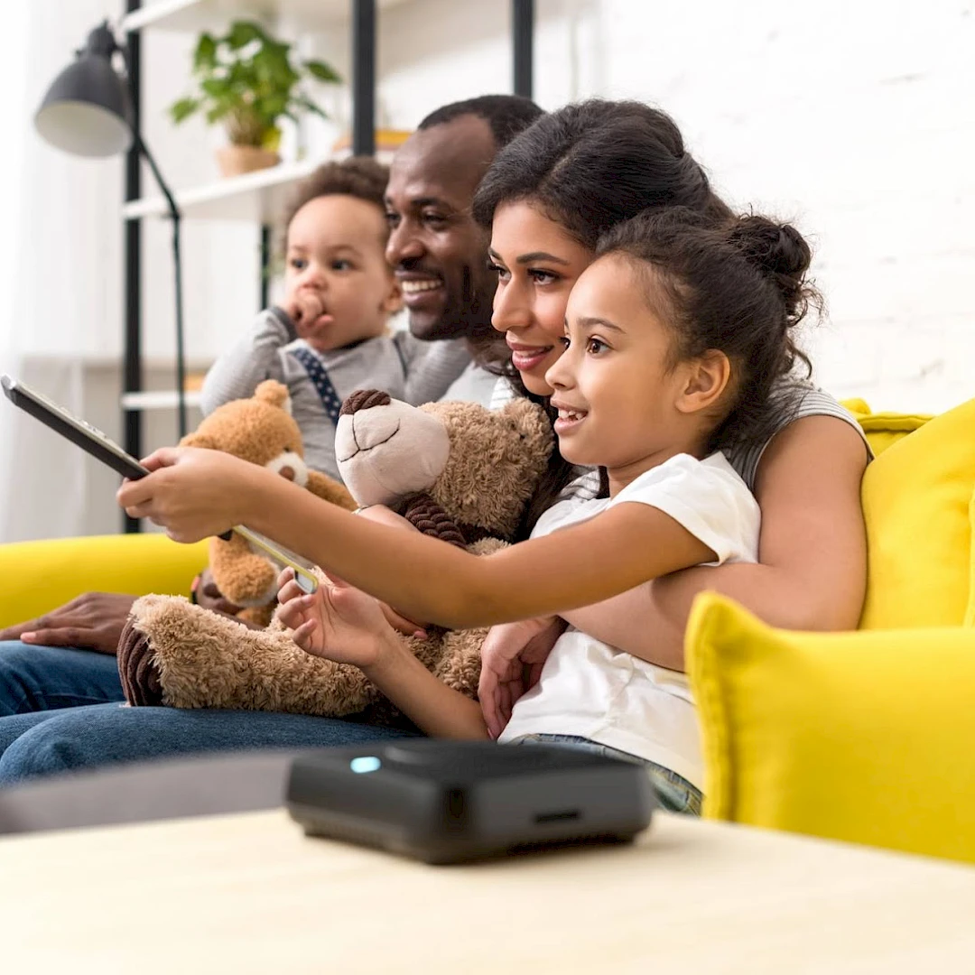 A family watching photos and videos on a television with an Amber X device in the foreground.