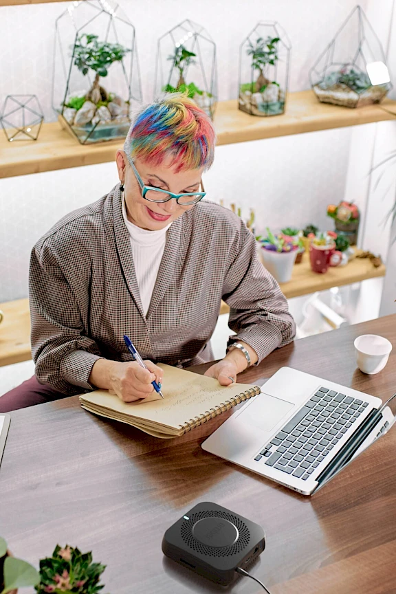 A woman working on her computer with an Amber device in the foreground.